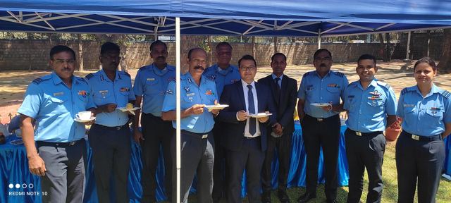 Team members standing with Air Force personnel in uniform under an open-air canopy during a tea break