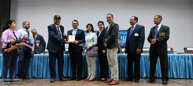 A memento being handed over on stage to team members in front of the dais