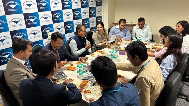 Team lunch meeting with fund industry partners in front of the Air Warrior Money backdrop