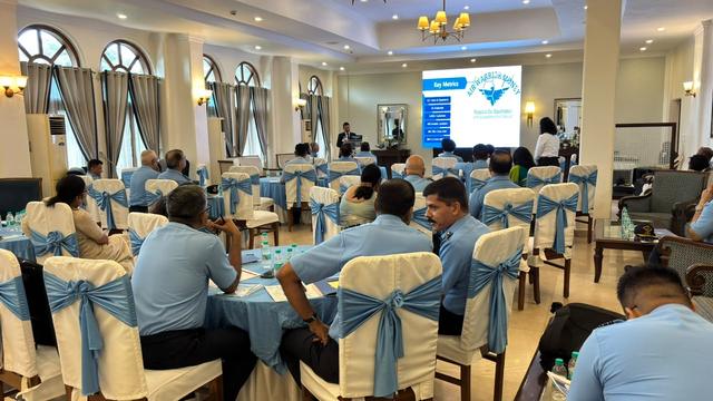 Presentation screen showing Air Warrior Money key metrics before a seated audience